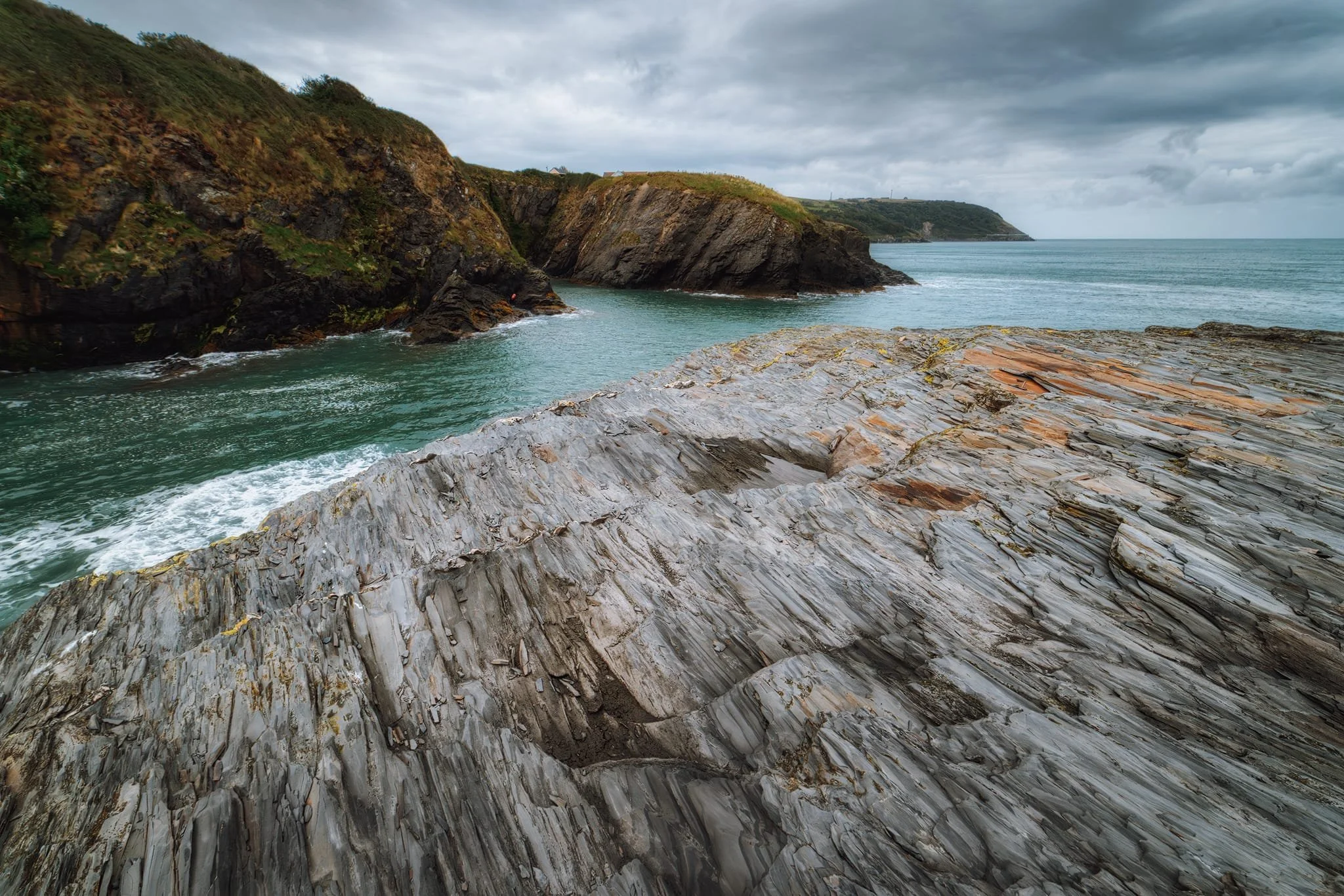 From the edge of the crag I got low to emphasise the amazing geology as a compositional aid towards the cliffs of Aberport. Even on a gloomy day, the waters here were still a beautiful azure.