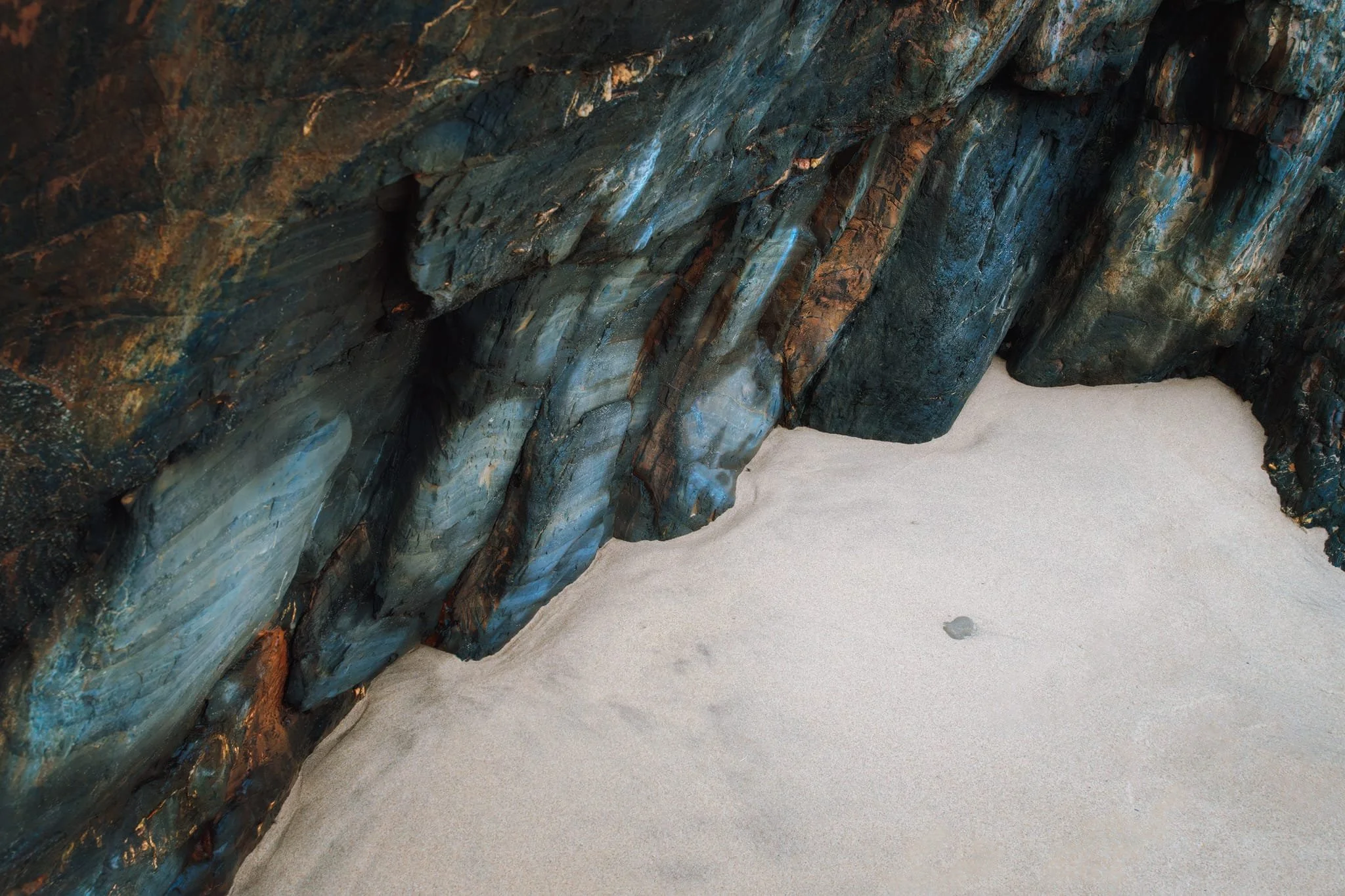 Eventually the path wound its way down steeply to Tresaith. We immediately scanned along the bottom of the southern cliffs, seeking compositions of the fascinating geology here. For this photo I spotted a secluded little cove within the cliffs, featuring virgin sand. I lined up this more abstract composition. I just like it.