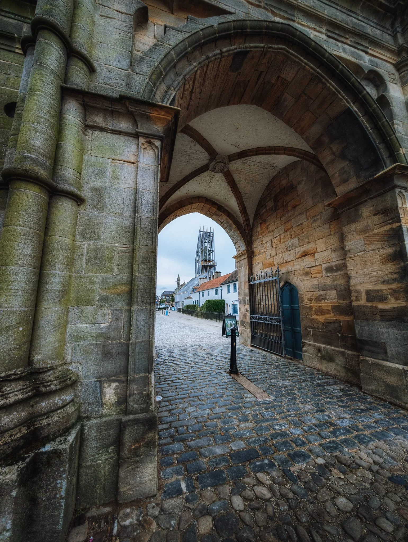The castle gateway, using the archway as a frame for Auckland Tower in the distance. The gateway was built in 1760 by Sir Thomas Robinson of Rokeby for Bishop William Trevor. By contrast, Auckland Tower was built in 2017. The form of the tower is intended to echo lightweight provisional structures that would’ve been used by invaders to breach castle walls.