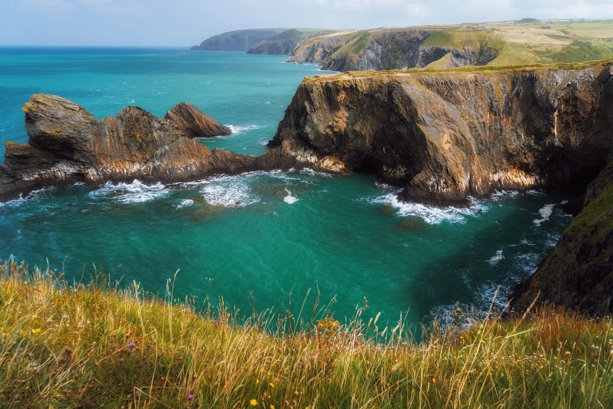 Heading further southwest before dropping down to Pwll y Wrach, a wide view opens itself to me, featuring a kaleidoscope of twisting sea stacks, gnarly cliff faces, secret sea caves, and everything in between. Around it all, wonderful azure tones in the water.
