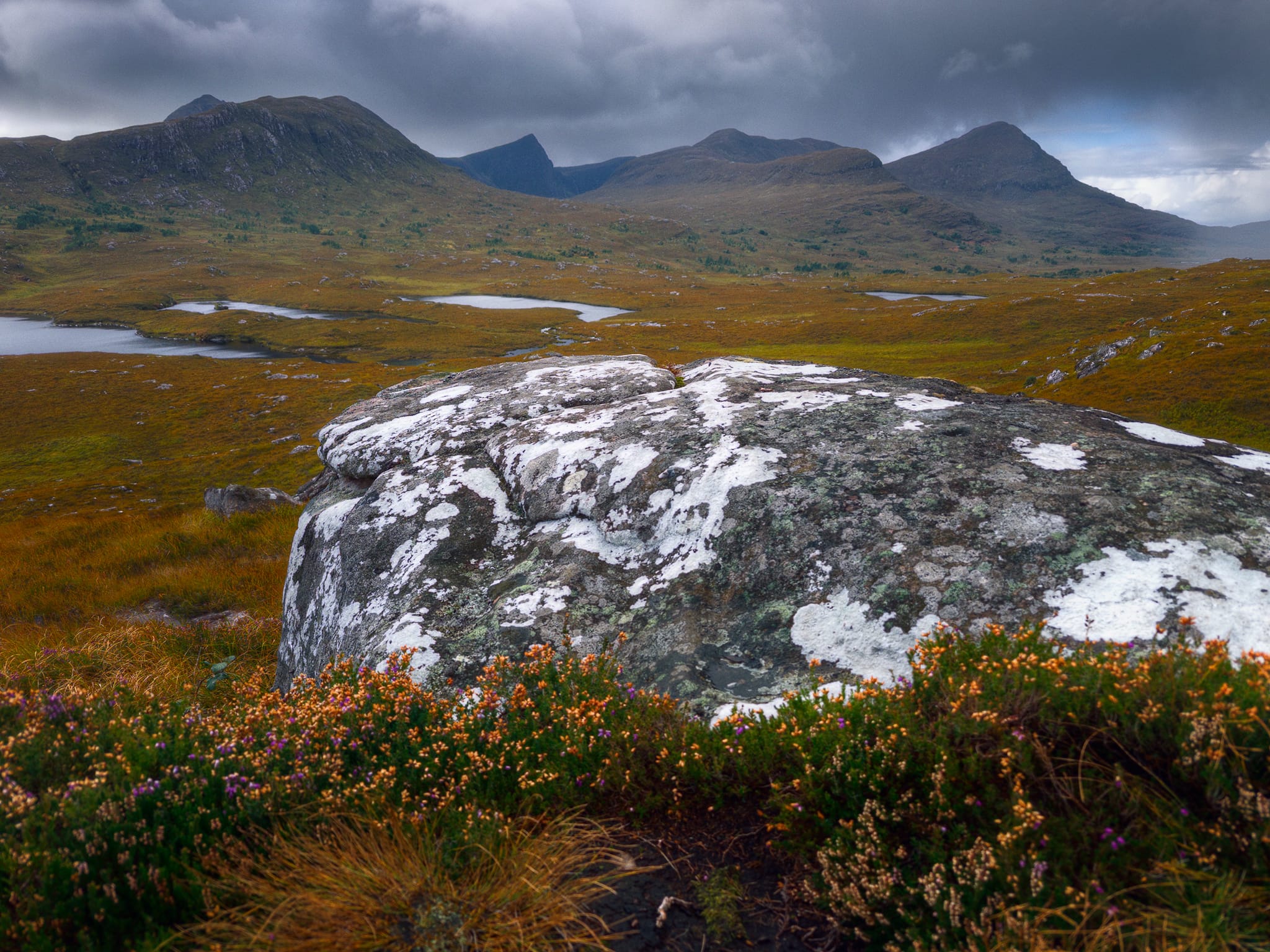 On another day we ventured off the main A835 road and took the minor road that travels underneath Cùl Beag and Stac Pollaidh. Conditions were initially, again, stormy. Along the single track road, a small layby was connected to a series of Torridonian sandstone outcrops that I had to stop at and play around for compositions. Here, I got tight and low with a lichen-covered boulder, framed above with the fantastic peaks of Ben More Coigach. Left is Beinn Tarsuinn, then the distant and astonishing pyramidal profile of Sgùrr an Fhidhleir. Centre-right is the smaller Cìoch Beinn an Eòin and right is Sgòrr Tuath.