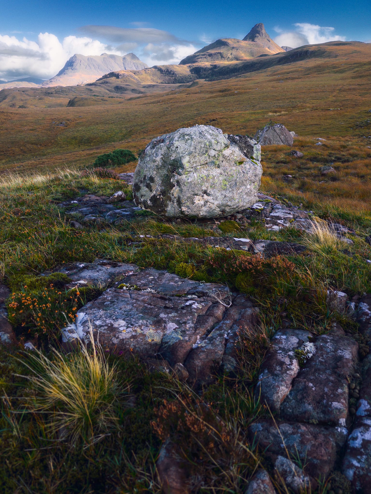 I knew on the moorland of Druim Bad a’ Ghaill that there were various sandstone outcrops with glacial erratics perched on them. I just didn&rsquo;t know where specifically. Thankfully, from near the power generator we parked near, I sighted a lone boulder perched on a platform further down the road. After some squelching and slipping, I found my composition that also happily included Stac Pollaidh and Cùl Mòr.