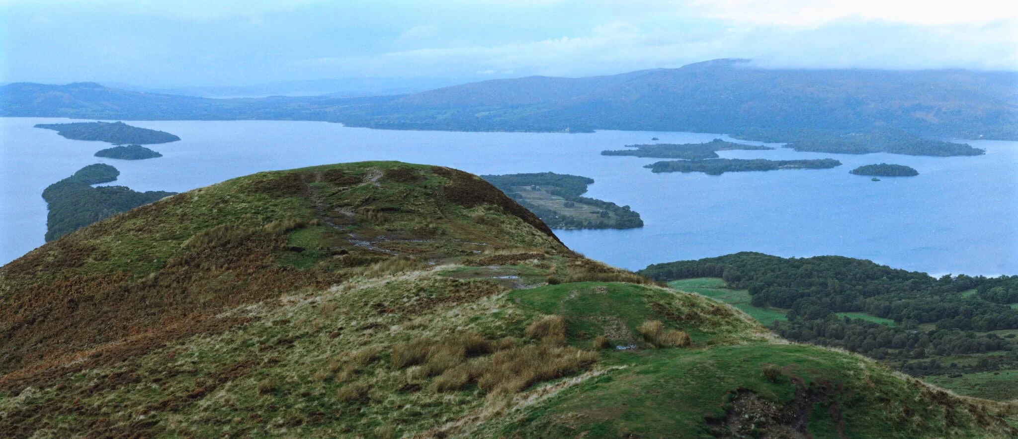 An 8-shot panorama from the summit of Conic Hill, looking down its ridge towards the islands of Loch Lomond and its western hills. Fantastic.
