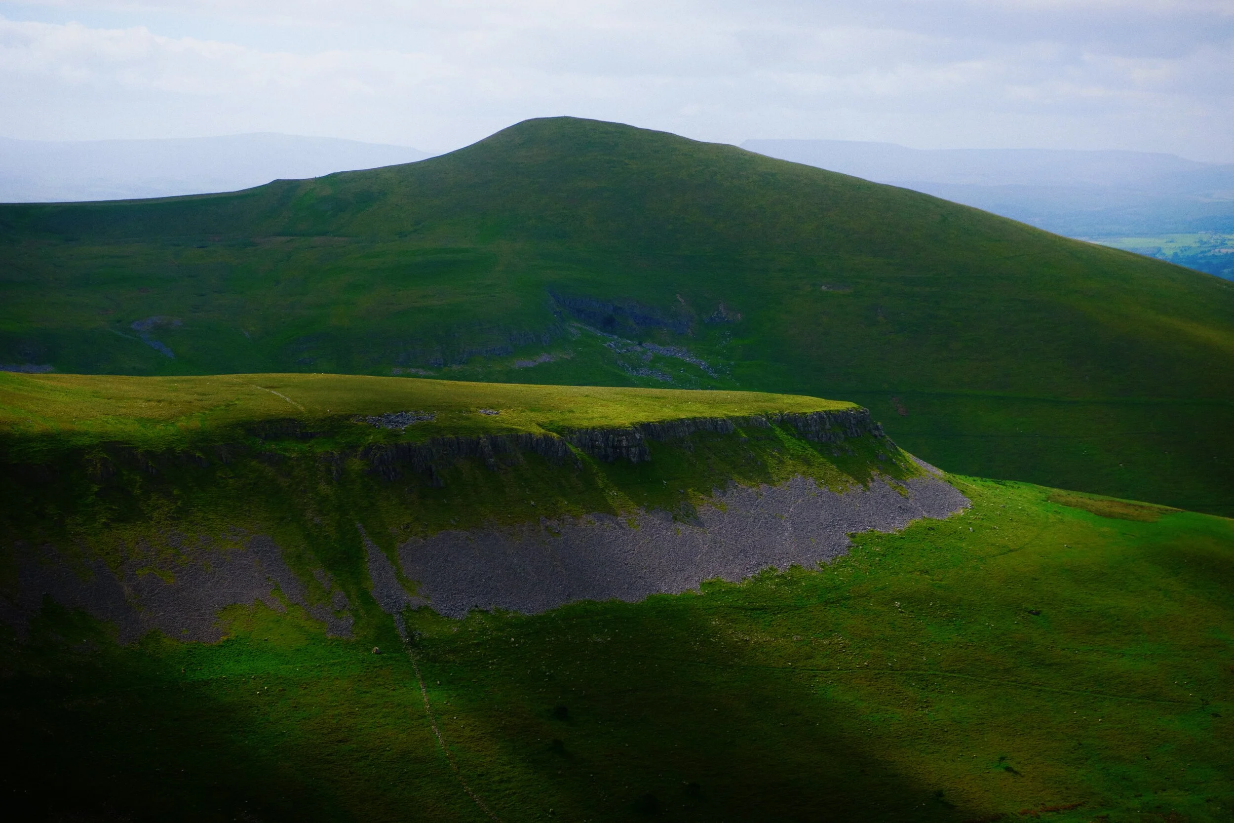 As we round the shoulder of Peeping Hill (510 m/1,673 ft) a look southeast reveals the flat-topped Middletongue Crag (456 m/1,496 ft) being highlighted, with Murton Pike’s (594 m/1,949 ft) gentle slopes looming above.