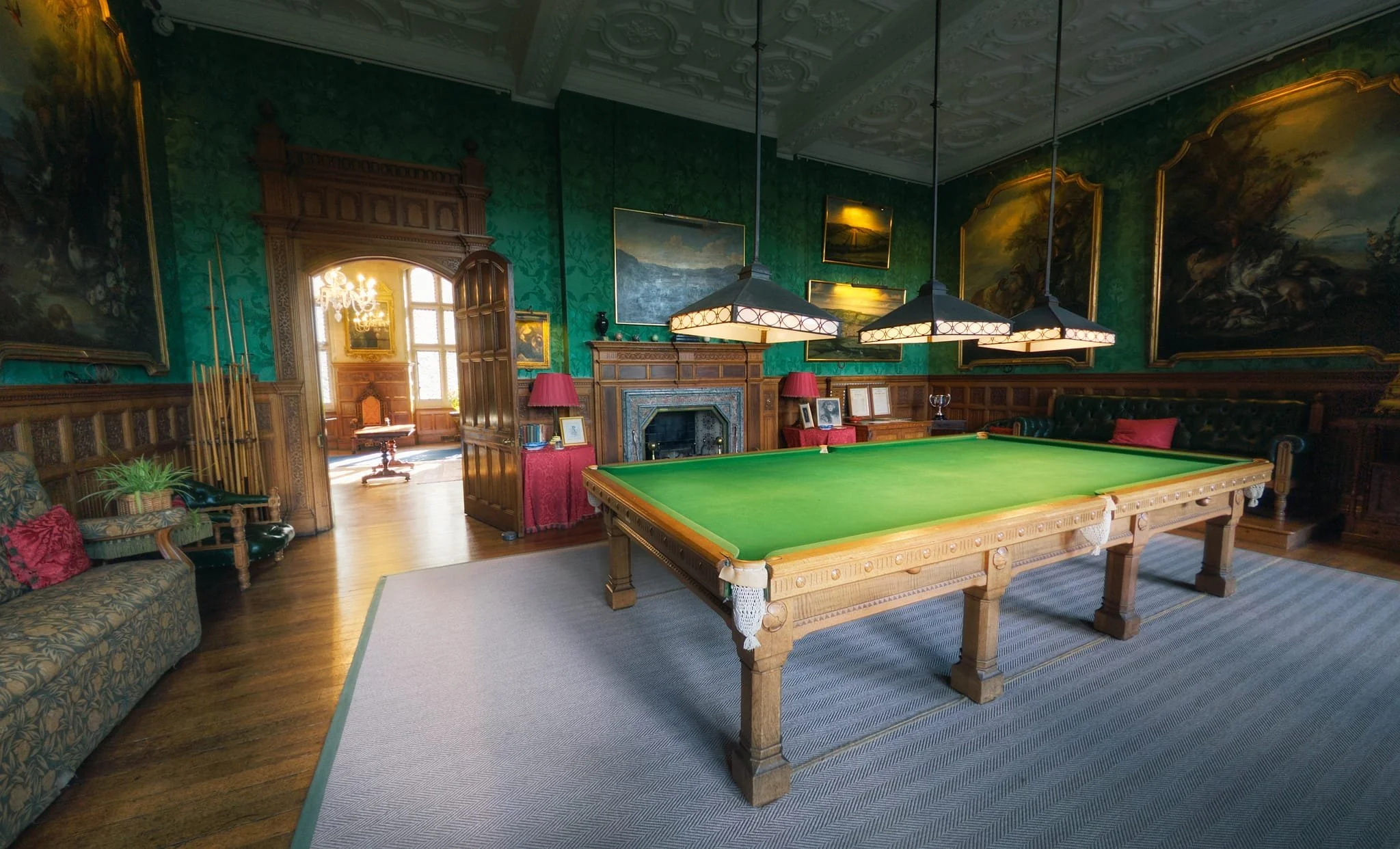 The Billiard Room, decorated with portraits and paintings and featuring a full-size billiards table.