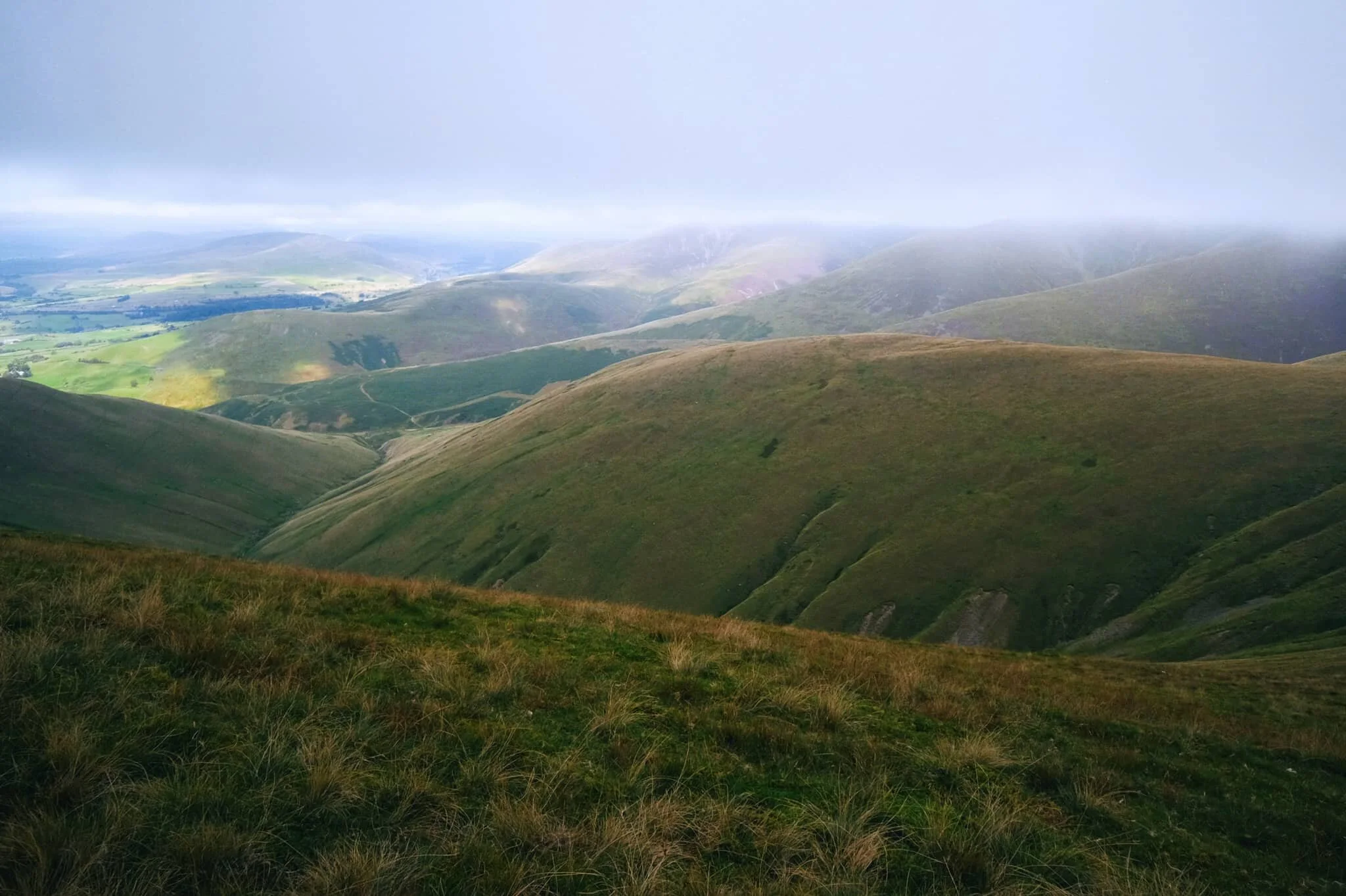 The views north from Arant Haw take in a succession of Howgills peaks and valleys, felltops such as Calders (674 m/2,211 ft), Bram Rigg Top (672 m/2,205 ft), The Calf (676 m/2,218 ft, highest point of the Howgills), and White Fell (636 m/2,086 ft). The clouds clung to the felltops as the day brightened
