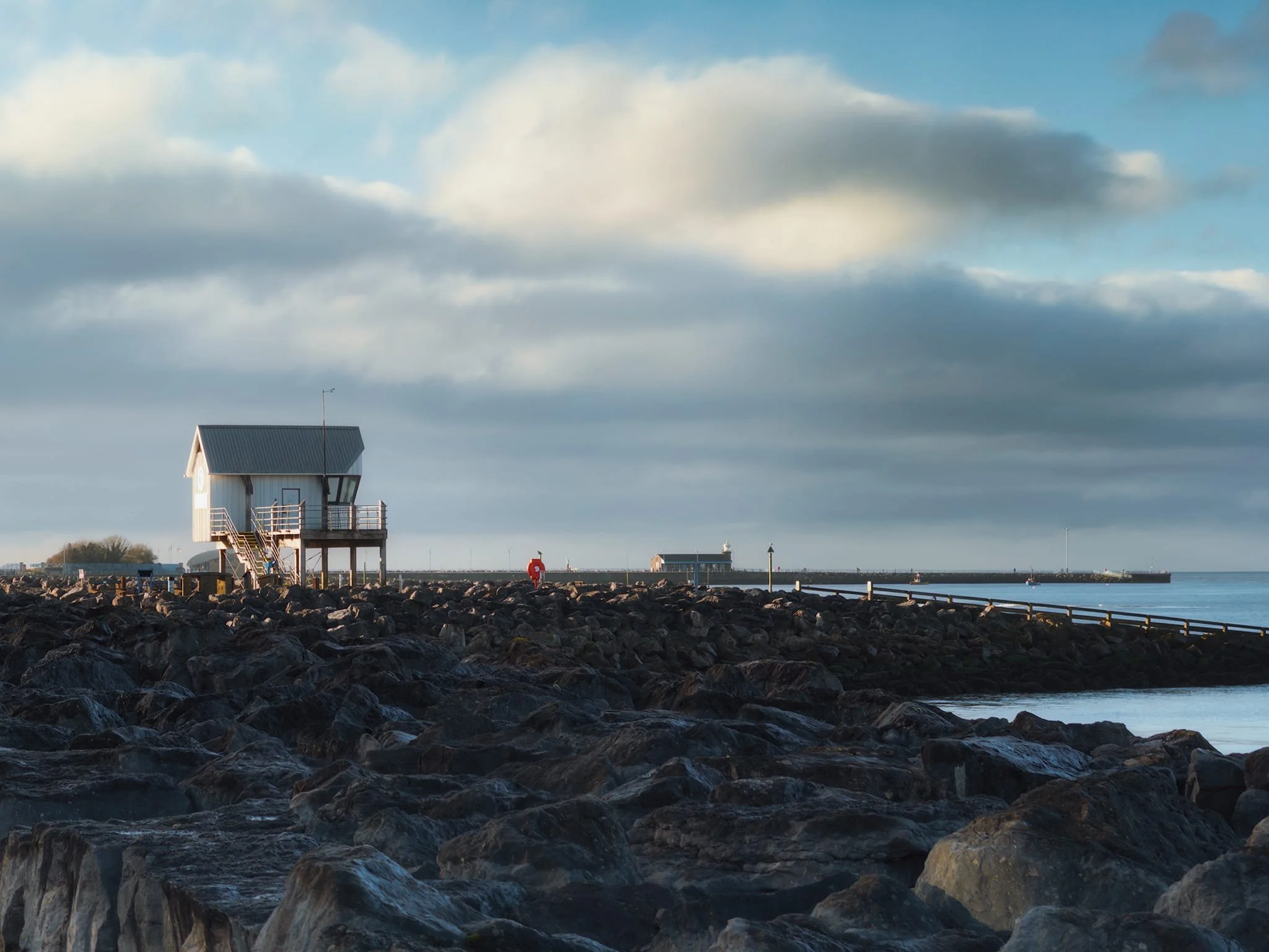 The boat office of Morecambe Sailing Club catching the brilliant winter light above Morecambe’s extensive boulder breakwaters. Rushing clouds above moved in.