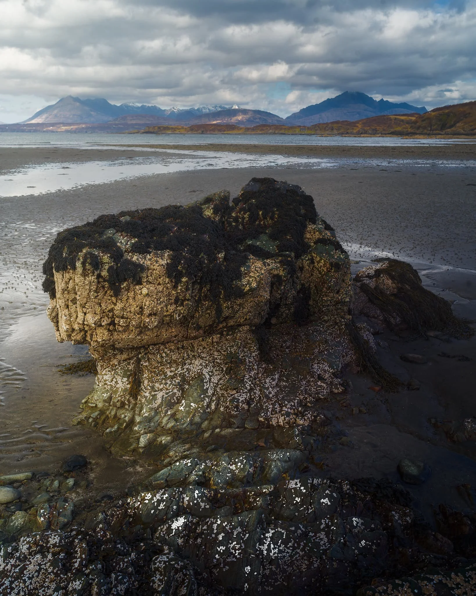 Away from the massive crag I head towards the more expansive beach, with fantastic clear views towards the Cuillins. I find another otherworldly rock formation and seek to compose along with the winding channels towards the Cuillins.