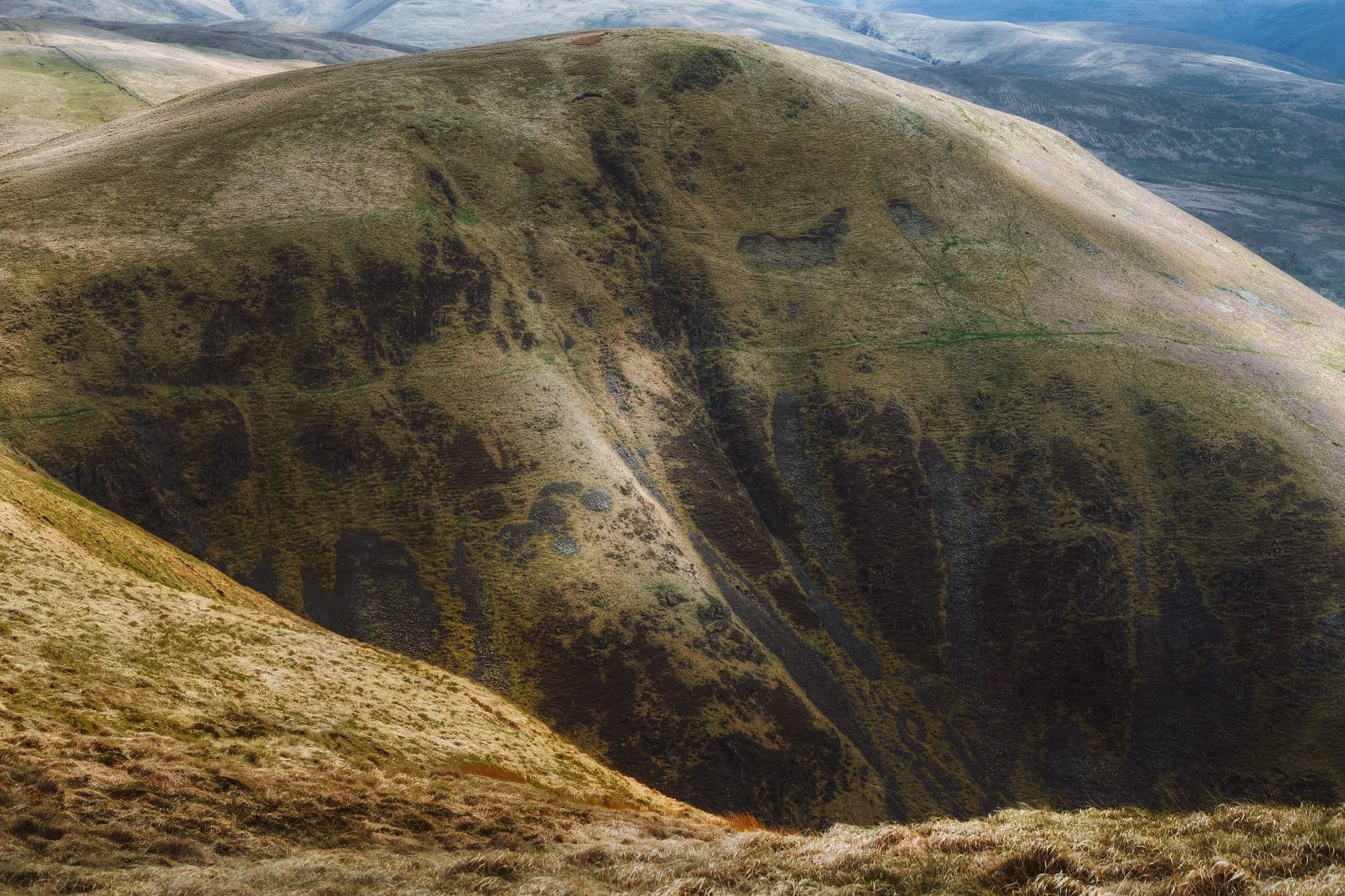 I couldn’t resist zooming in on the impressively steep and scarred western face of Great Hill, as the light gently scanned across its features. Summitting Great Hill was our next goal but even in dry conditions the path up to its peak was a veritable quagmire so we backed off and head back. Maybe another time.