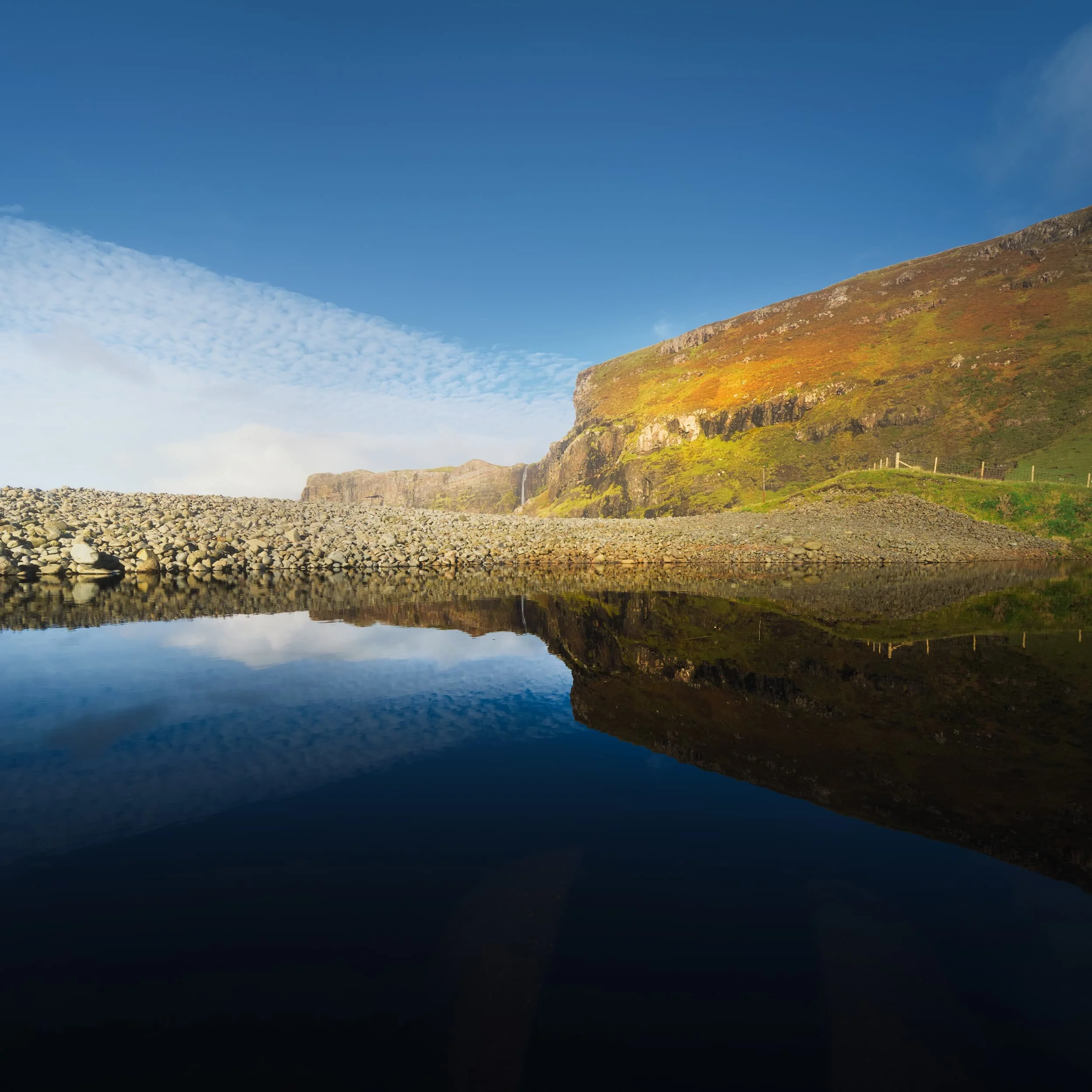 The northern side of Talisker Bay features sheer cliffs and a delightful waterfall dropping right into the sea. The waterfall is the outflow from a small loch just above the cliffs, Loch an Sgùirr Mhòir .