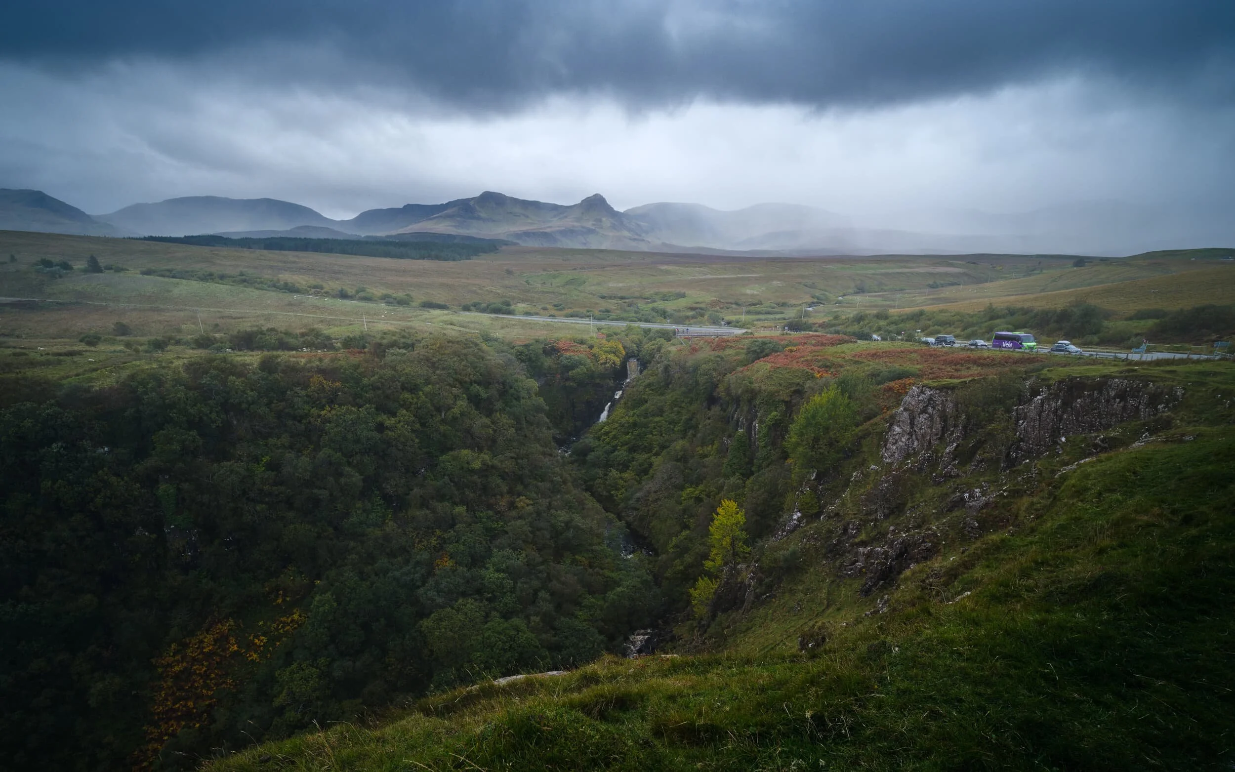 A panoramic view of the gorge that the Lealt Falls have cut, whilst a heavy storm drenches the peaks of the Trotternish landslip.