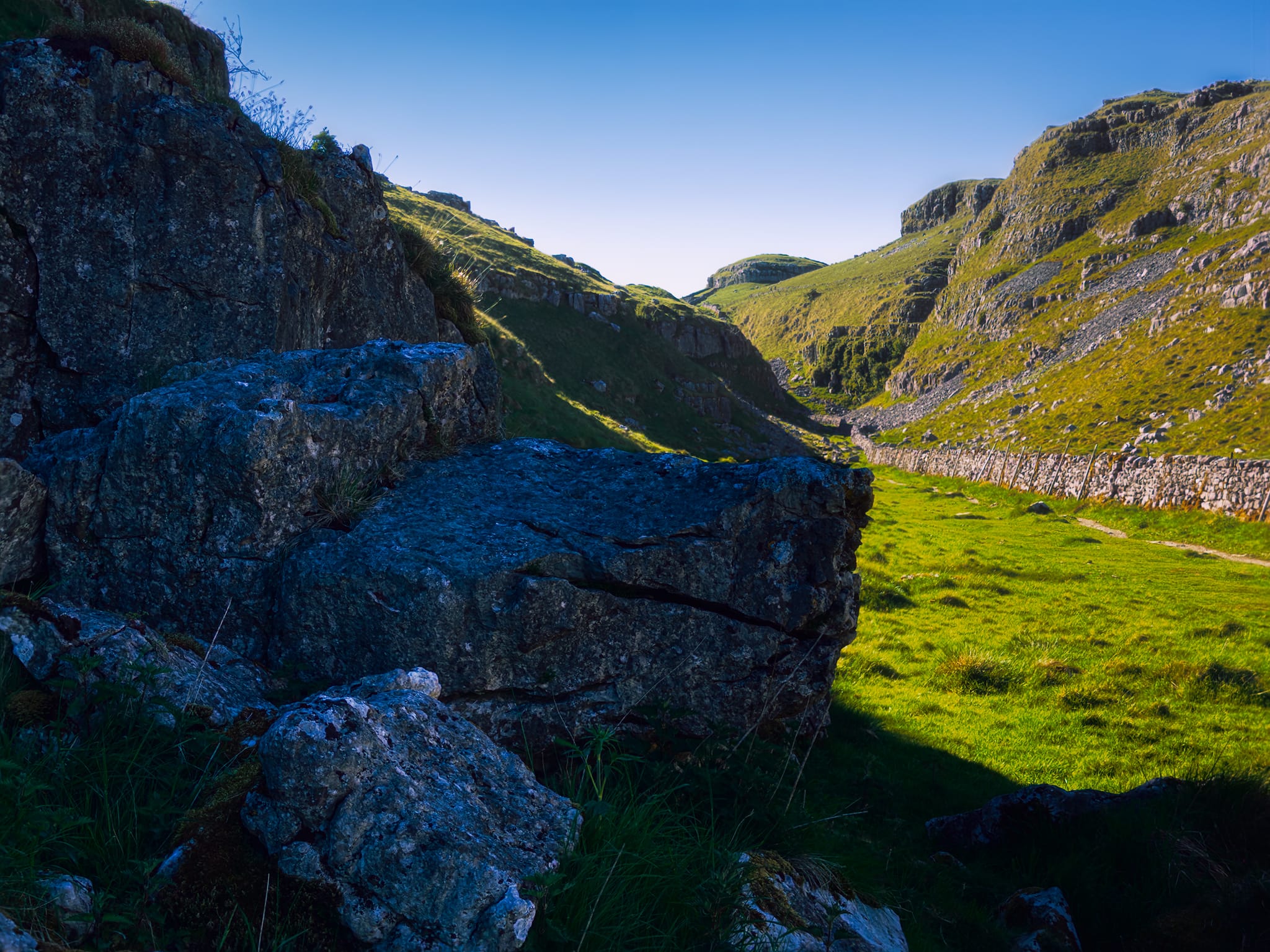 Another cluster of limestone boulders deep in the shade provide another contrasting composition with the valley&rsquo;s high crags towering above.